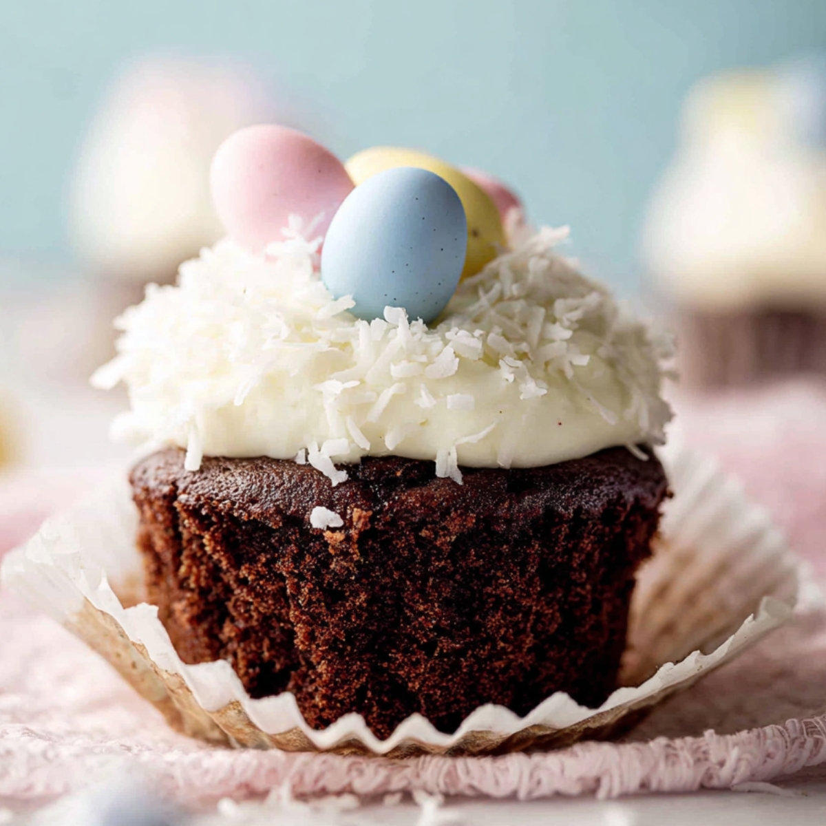 Homemade Coconut Chocolate Easter Cupcakes with coconut frosting, pastel candy eggs, and a soft cupcake interior.