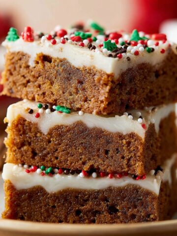 Homemade Gingerbread Cookie Bars with a thick layer of white frosting, decorated with colorful sprinkles on top.