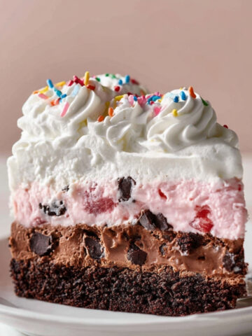 Homemade Ice Cream Cake Recipe | 6 Ingredients, No Bake 16 Slice of layered Ice Cream Cake Recipe with brownie base, chocolate layer, strawberry ice cream, and whipped cream topping