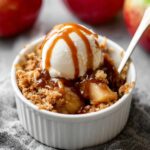 Individual Apple Crumbles topped with vanilla ice cream and caramel sauce.