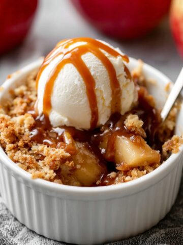Individual Apple Crumbles topped with vanilla ice cream and caramel sauce.