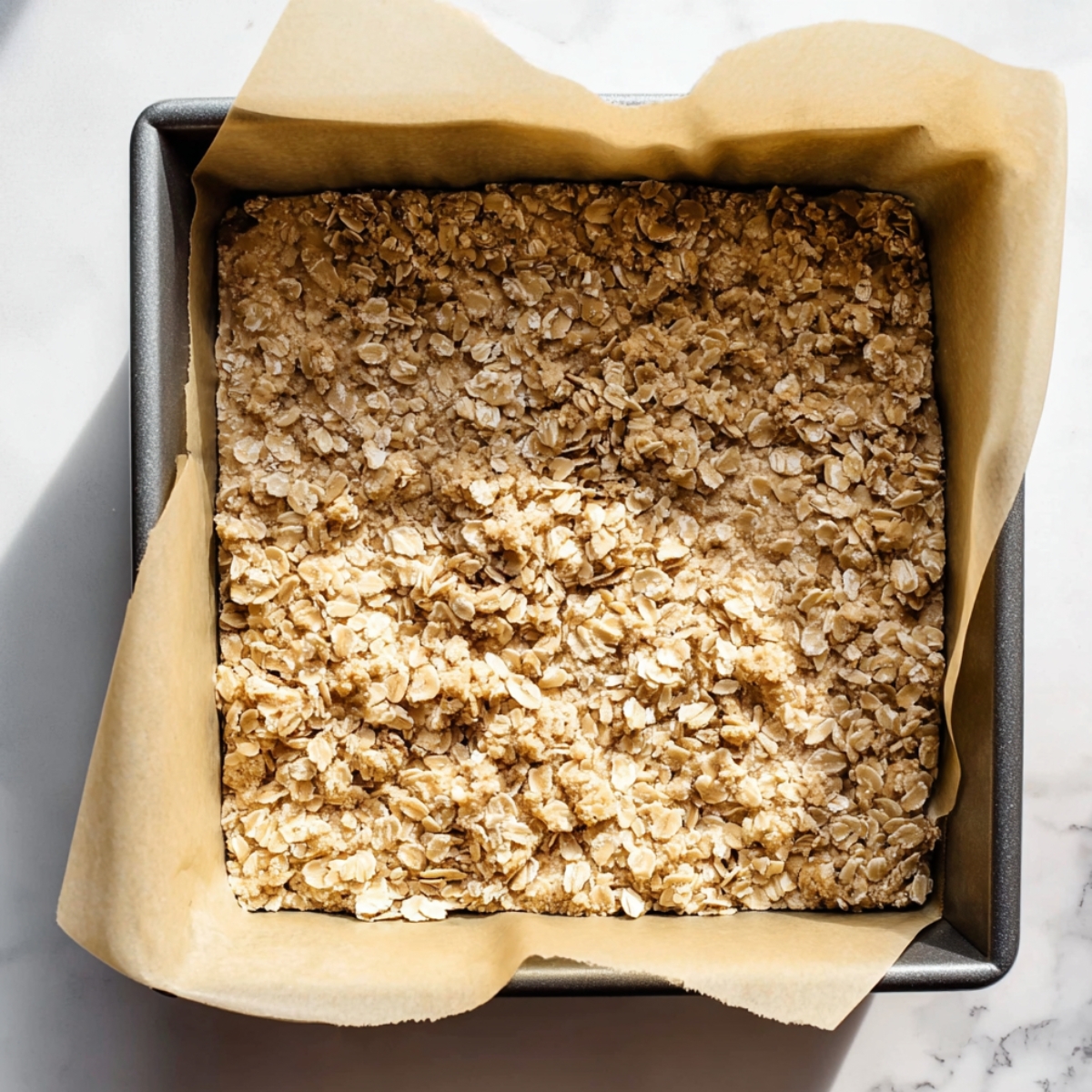 Oatmeal Lemon Crumble Bars Recipe 11 Oatmeal crumble mixture pressed into a parchment-lined baking pan for lemon crumble bars