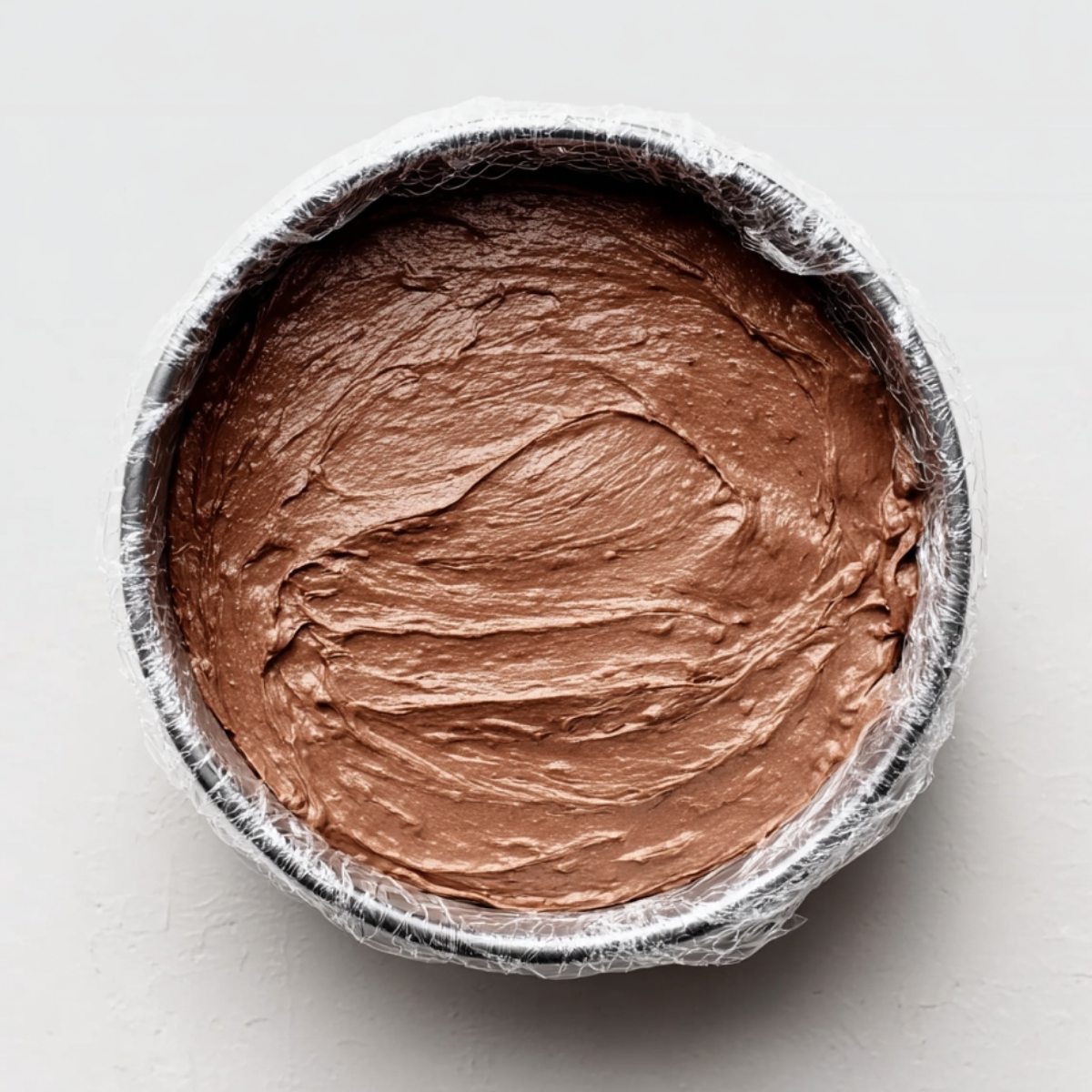 Homemade Ice Cream Cake Recipe | 6 Ingredients, No Bake 11 Chocolate ice cream layer spread smoothly into a round cake pan lined with plastic wrap