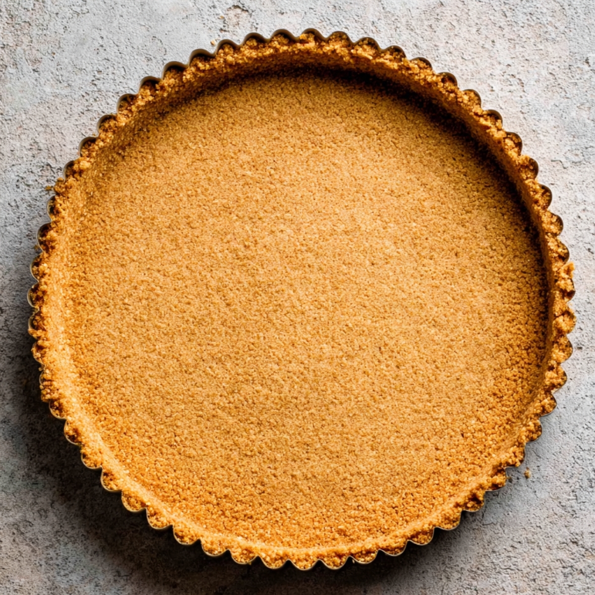 Peanut Butter Cup Tart 10 Golden graham cracker crust in a tart pan, ready to be filled with a creamy filling, showing the perfectly fluted edges.