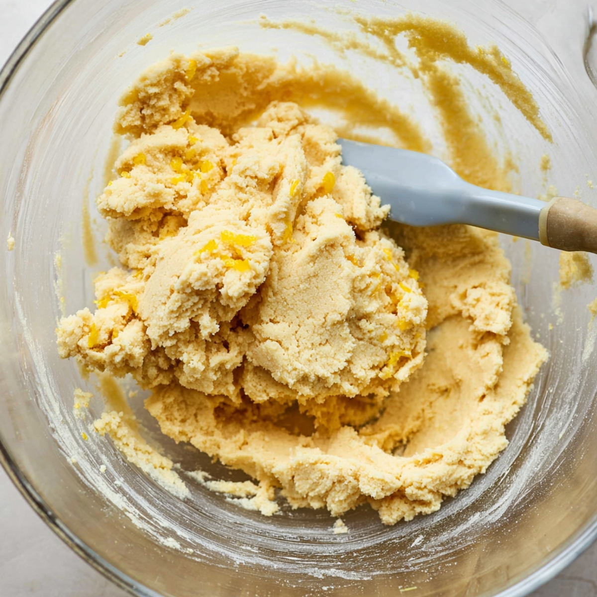 Easy Lemon Shortbread Cookies Recipe 11 Lemon shortbread dough in a glass bowl, mixed and ready to be rolled out, with visible lemon zest throughout the dough.