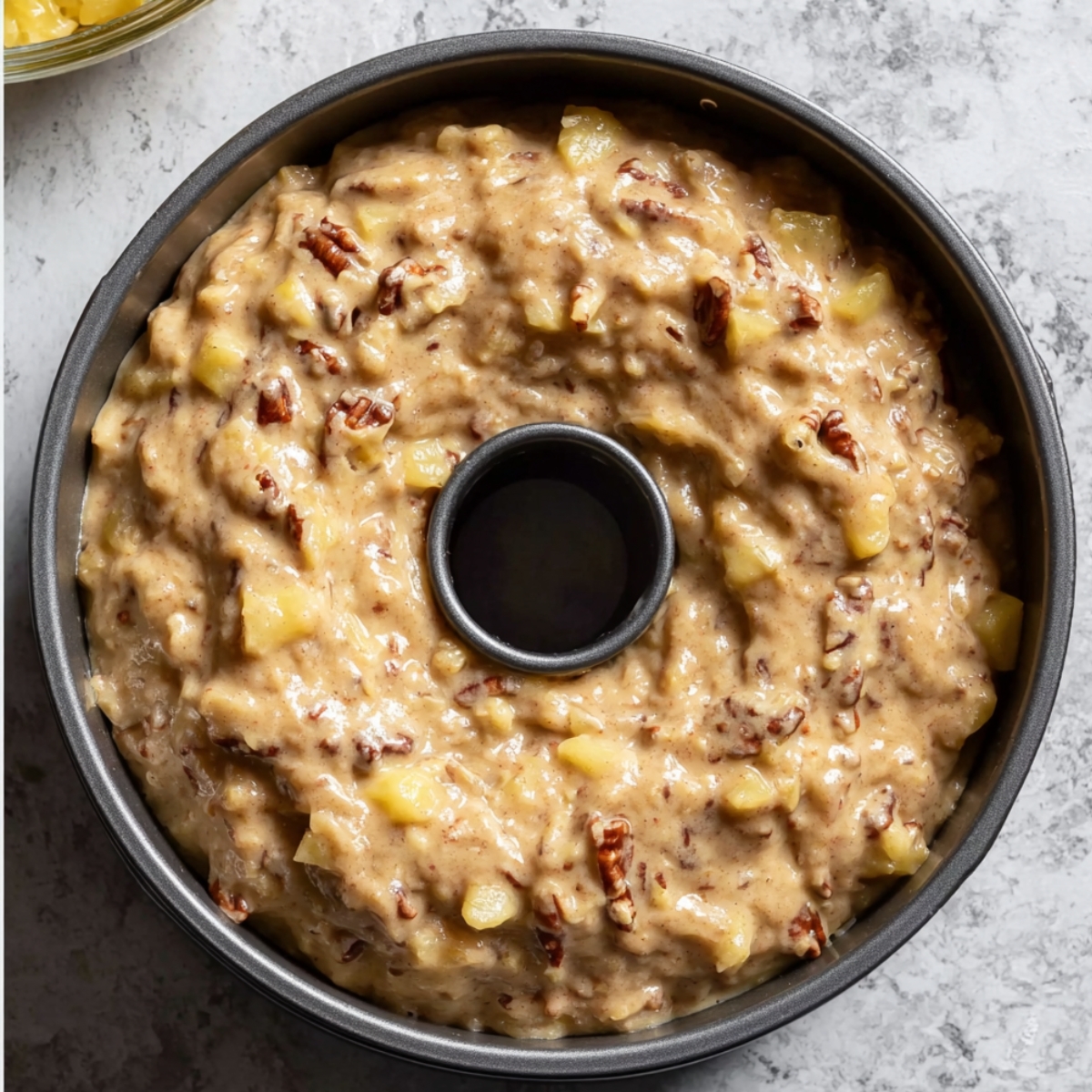 Hummingbird Bundt Cake Recipe | Moist & Easy 11 Unbaked hummingbird cake batter with pineapple and pecans poured into a bundt pan