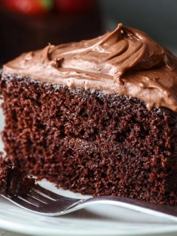Moist Chocolate Mayonnaise Cake 12 A close-up of a slice of Moist Chocolate Mayonnaise Cake with frosting, sitting on a plate.