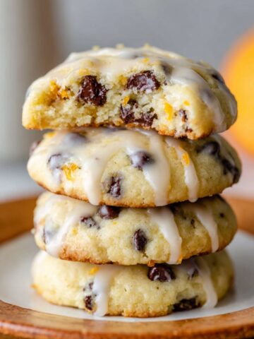 Orange Chocolate Chip Ricotta Cookies 3 Stacked Orange Chocolate Chip Ricotta Cookies with a sweet glaze, one of which is broken in half to reveal the soft, chocolate-filled interior, perfect for a citrusy, chocolatey treat.
