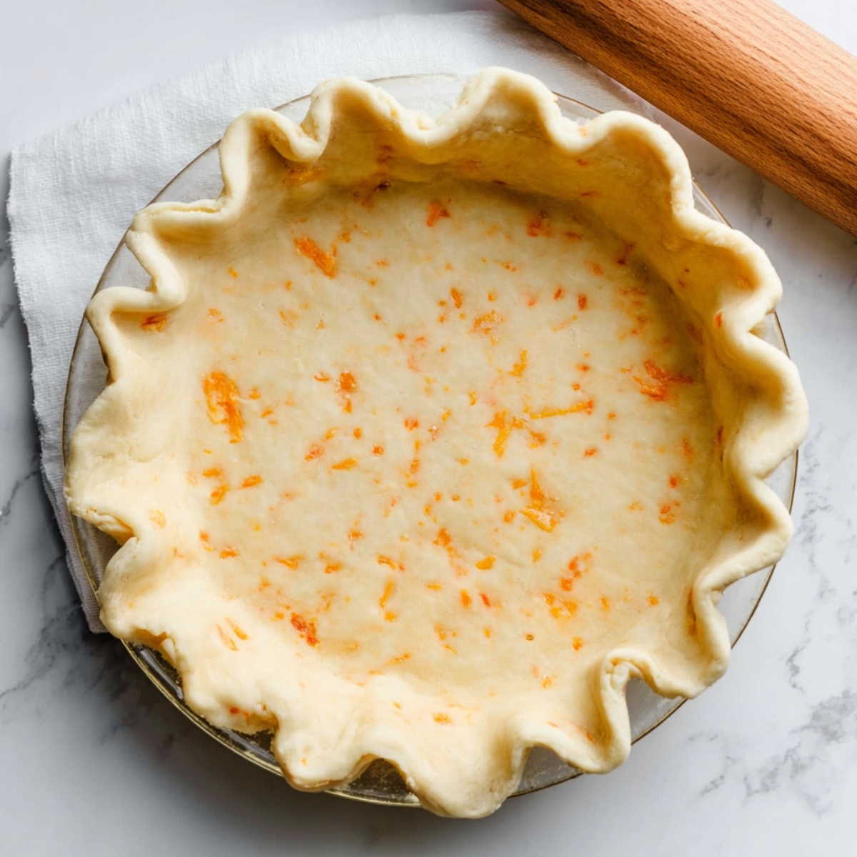 Easy Apple Cheddar Pie | Homemade Savory-Sweet Pie 11 Unbaked cheddar cheese pie crust pressed into a glass pie dish with fluted edges on a marble countertop