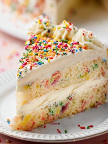 Perfect One Layer Sprinkle Cake Recipe 15 A slice of Sprinkle Cake on a plate with colorful sprinkles on top and visible sprinkles throughout the cake layers.
