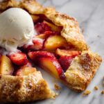 Close-up of Strawberry Peach Galette slice with flaky crust and melting vanilla ice cream