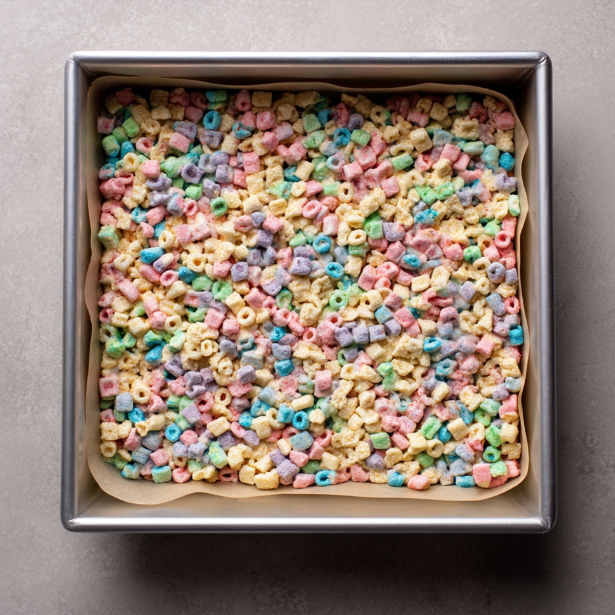 A square pan filled with colorful Lucky Charms cereal treats, pressed and ready to be cut.