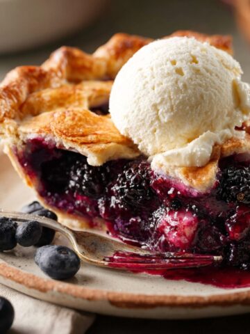 Triple Berry Pie slice topped with melting vanilla ice cream