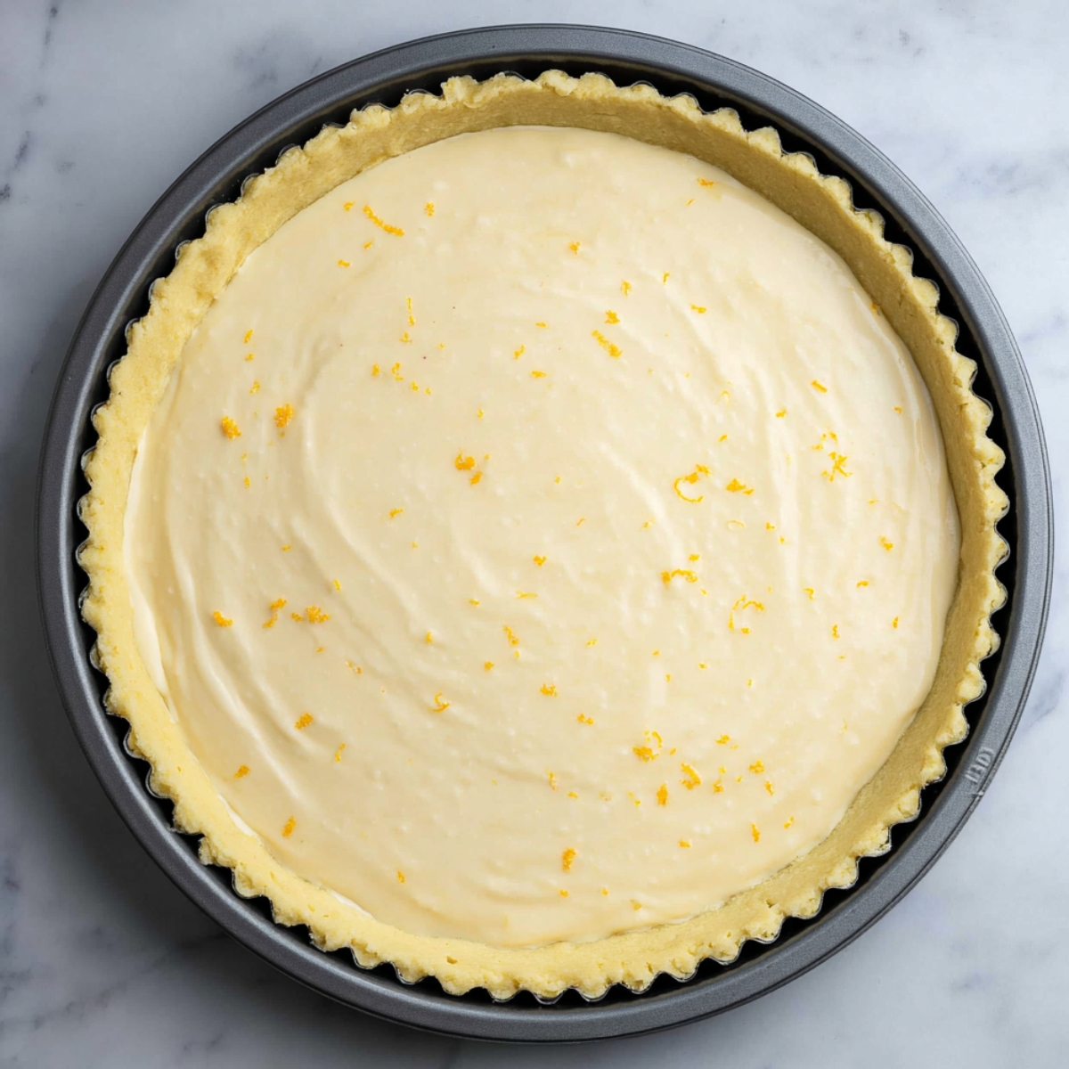 Best Greek Honey Pie Recipe 13 A smooth, creamy filling for Greek honey pie being poured into the prepared tart crust, topped with lemon zest for a burst of citrus flavor.