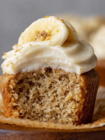 The Best Banana Cupcakes Recipe 1 Banana Cupcakes with cream cheese frosting topped with a banana slice and crumbled graham crackers.