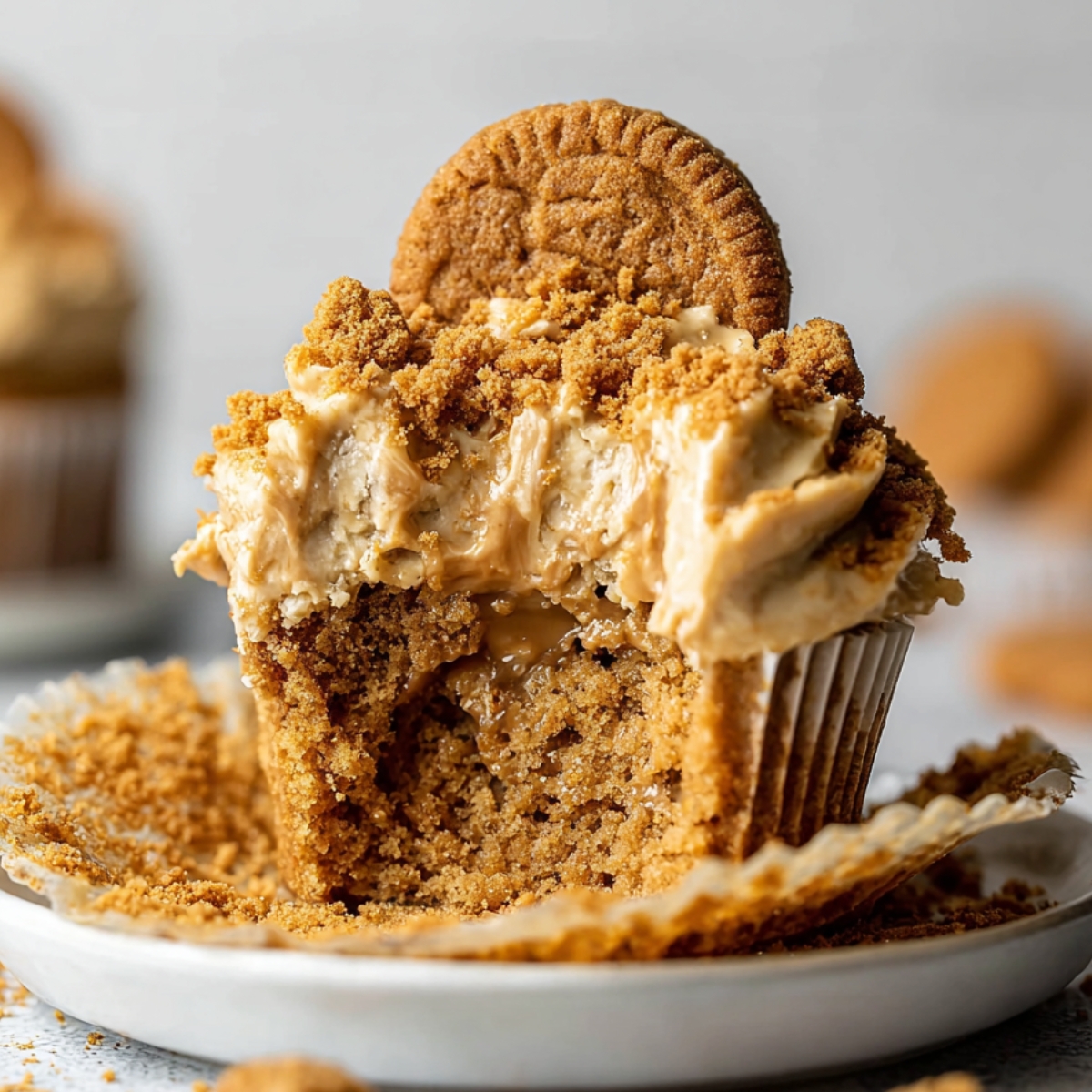 The Best Biscoff Cupcakes Recipe 9 Close-up of a bowl filled with Biscoff Cupcakes, showing the chocolate-covered exterior with a bite taken out revealing the smooth peanut butter filling.
