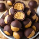 Close-up of homemade Buckeyes Recipe, chocolate-covered peanut butter balls with a bite taken out, showing the smooth peanut butter filling.
