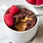 A warm, freshly baked Chocolate Mug Cake with a gooey peanut butter center, ready to be enjoyed with a spoonful of indulgence.