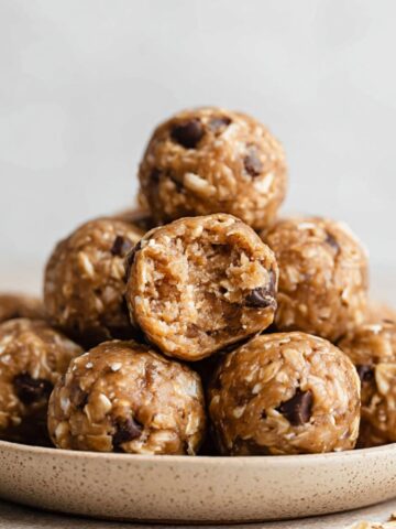 Chocolate Peanut Butter Protein Balls 1 A pile of Chocolate Peanut Butter Protein Balls with one ball cut open, showing the texture of oats and chocolate chips.