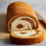 A freshly baked Coffee Swiss Roll with creamy filling, cut into slices.