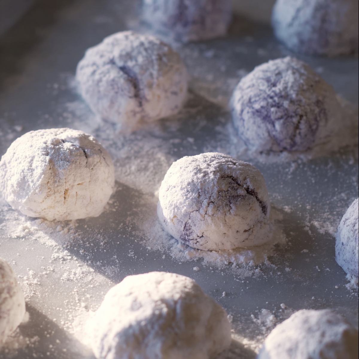 Easy Ube Crinkle Cookies Recipe 11 Ube Crinkle Cookie dough balls coated in powdered sugar, ready to bake, showing the snowy appearance before the crinkling begins in the oven.