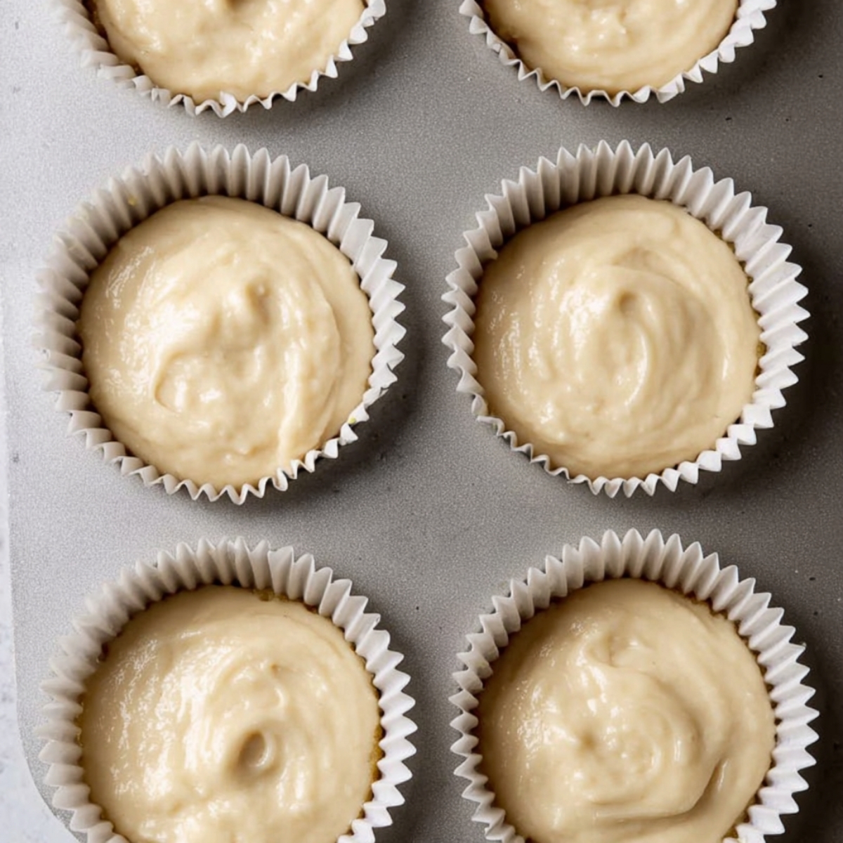 The Best Biscoff Cupcakes Recipe 11 Close-up of Biscoff cupcake batter filled into cupcake liners in a tray.