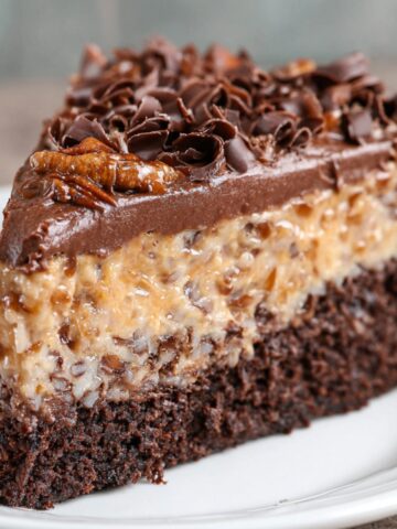 Easy German Chocolate Cheesecake Recipe 1 A slice of German chocolate cheesecake topped with pecans, coconut, and chocolate frosting.