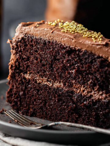 Moist Guinness Chocolate Cake Recipe 5 A slice of Guinness Chocolate Cake with smooth chocolate frosting and golden sprinkles on top. The rich, dark cake layers are moist, and the frosting is beautifully spread between the layers.