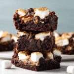 A stack of marshmallow brownies with gooey marshmallow and melted chocolate chips inside, topped with toasted marshmallows.
