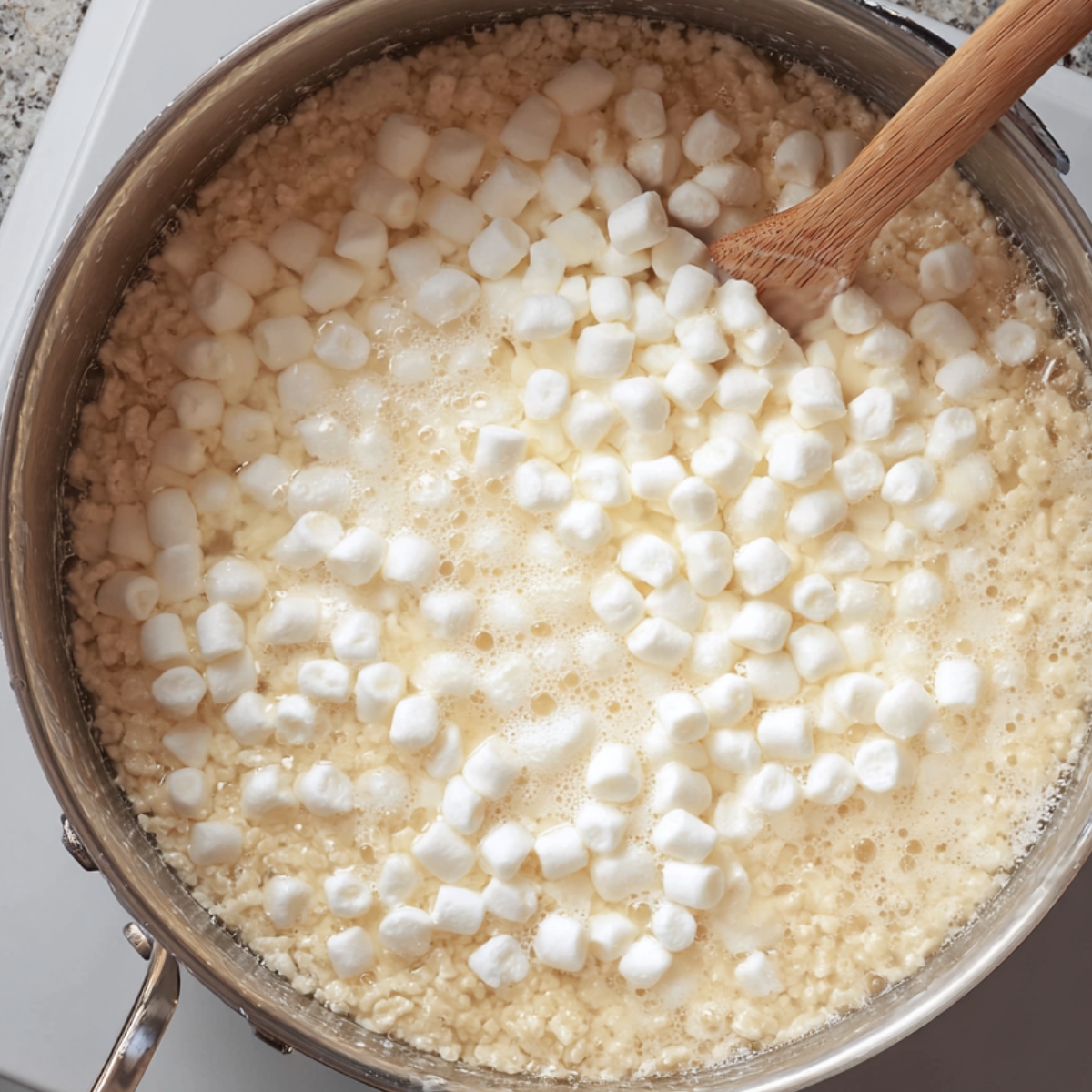 Pumpkin Spice Rice Krispies Recipe 10 A large pot on the stove with marshmallows melting with butter, showing some mini marshmallows floating in the melted mixture, ready to be stirred together.