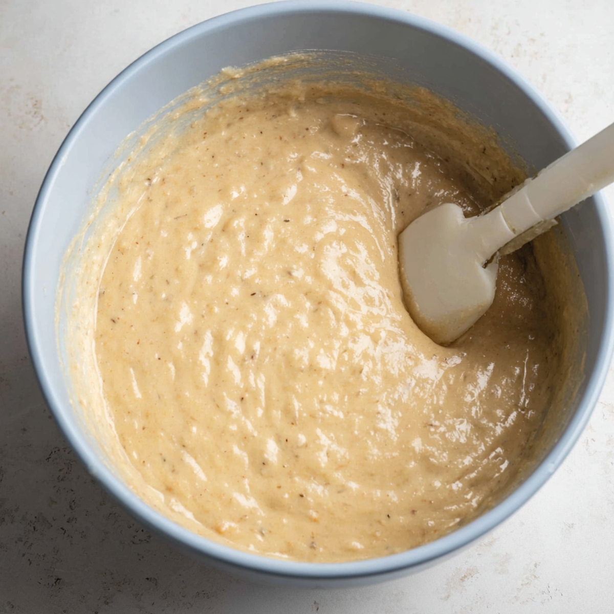 Easy Peanut Butter Banana Cake 11 A bowl with cake batter, showing the process of mixing in dry ingredients, resulting in a smooth, creamy mixture.