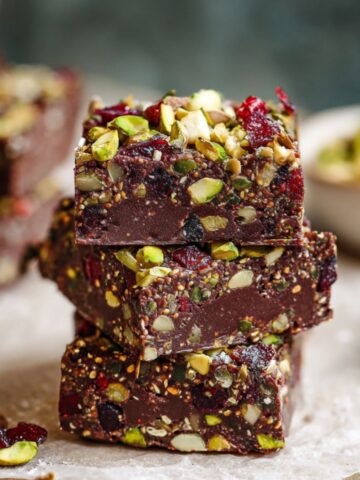 Healthy No Bake Superfood Brownies 1 A close-up of stacked No Bake Superfood Brownies, studded with pistachios and dried cranberries, offering a rich, nutrient-packed treat.