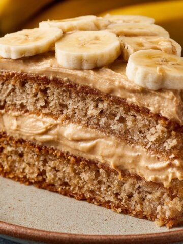 Easy Peanut Butter Banana Cake 1 A slice of moist Peanut Butter Banana Cake with creamy peanut butter frosting, topped with fresh banana slices, showcasing the soft texture and layered appearance of the cake.