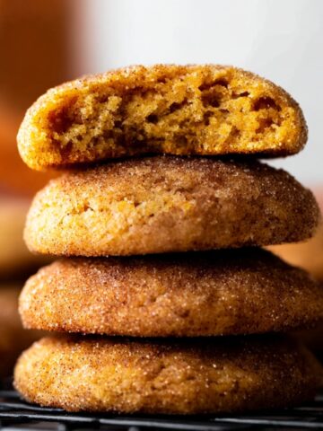 Chewy Pumpkin Snickerdoodles Recipe 2 Soft and chewy Pumpkin Snickerdoodles cookies, coated in cinnamon-sugar, with a bite taken out to reveal their fluffy, spiced interior.