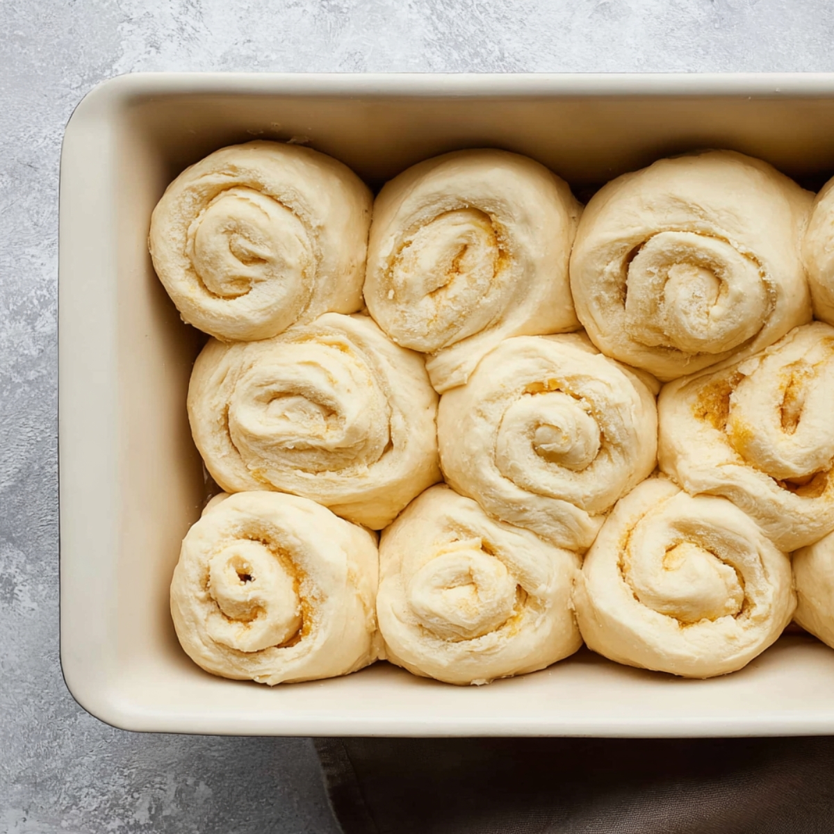 Homemade Orange Rolls Recipe 12 Soft, unbaked orange rolls arranged in a baking dish, ready to rise and be baked into fluffy, golden rolls.