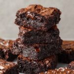 Decadent stack of fudgy Small Batch Brownies, with visible cracks on the top and gooey melted chocolate chunks peeking through.