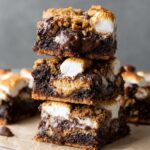 Stacked S'mores Brownies with gooey chocolate, marshmallows, and graham cracker crust, showcasing their delicious layers.