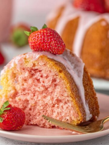 Delicious Strawberry Bundt Cake Recipe 1 A slice of Strawberry Bundt Cake topped with fresh strawberries and glaze, showing a soft, fluffy pink interior and a light pink glaze.