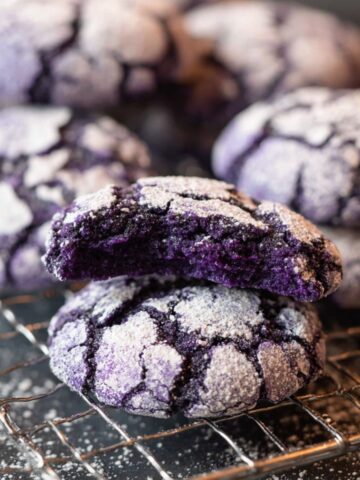 Easy Ube Crinkle Cookies Recipe 1 Freshly baked Ube Crinkle Cookies with vibrant purple centers and powdered sugar crusts, displaying their signature crinkled texture.