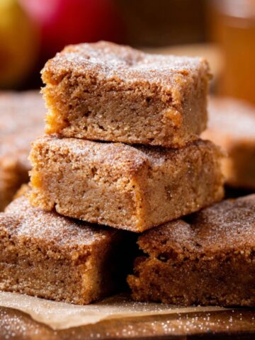 A stack of freshly baked Apple Cider Blondies, dusted with sugar, with a golden-brown color and a soft, crumbly texture.