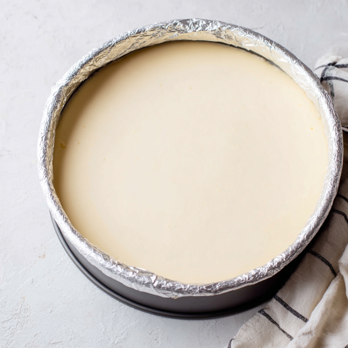 A cheesecake filling poured into a springform pan, with a smooth and even surface, ready to be baked.