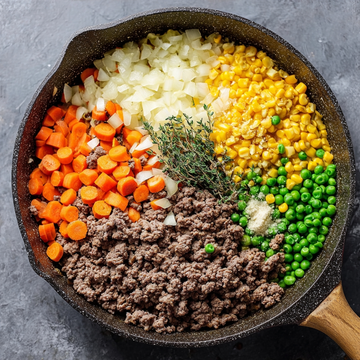 Cottage Pie with Garlic Mashed Potatoes 10 A skillet filled with ground beef, diced carrots, onions, peas, corn, and fresh thyme, seasoned and ready to be combined for a delicious cottage pie filling.