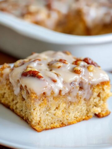 Slice of Butter Pecan Praline Poke Cake with glaze and pecans.