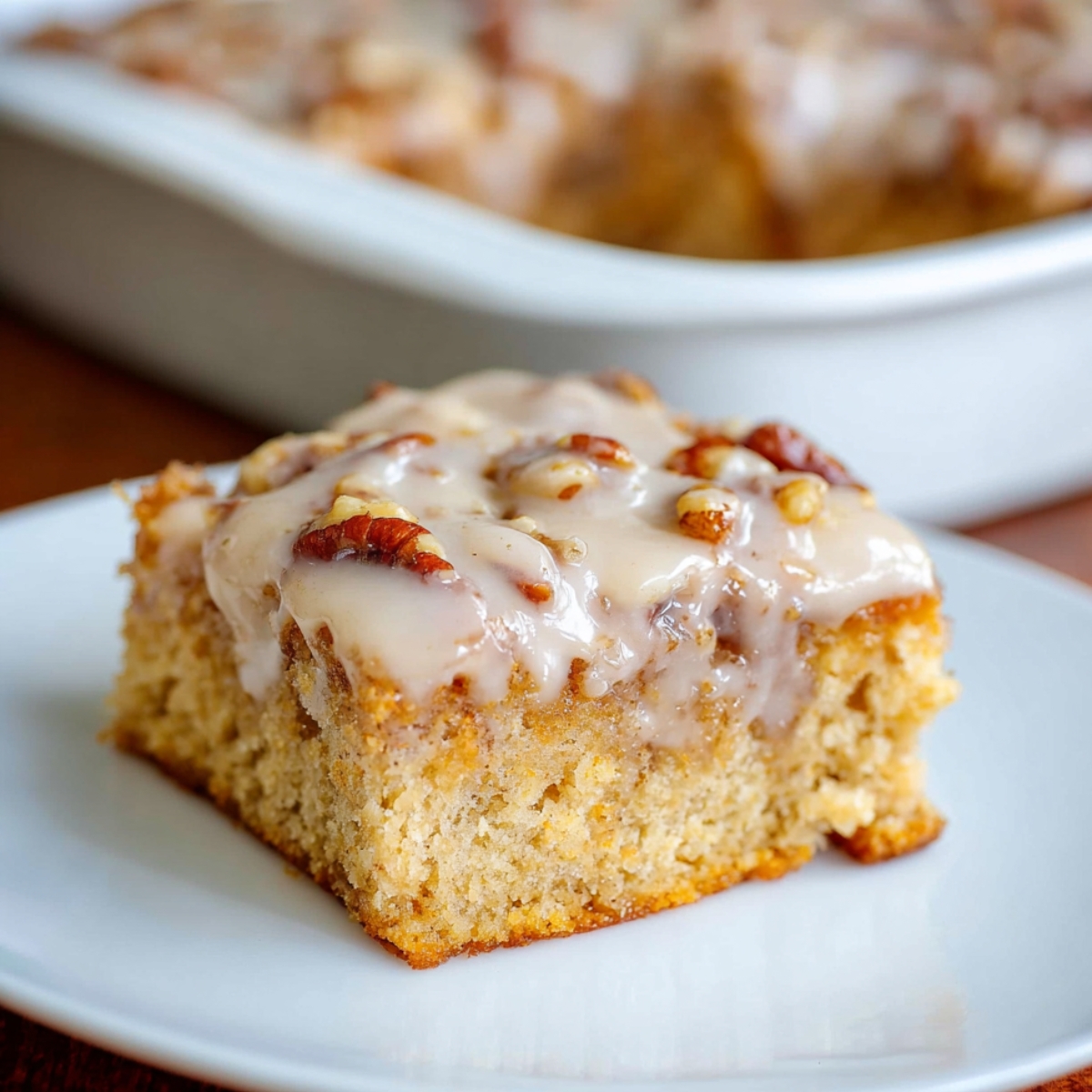 Slice of Butter Pecan Praline Poke Cake with glaze and pecans.