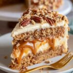 A slice of Butterscotch Crunch Cake with a caramel filling, topped with crushed pecans and frosting.