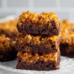 A stack of Caramel Crunch Brownies with a layer of crispy cornflakes on top, showing the rich, fudgy chocolate base.