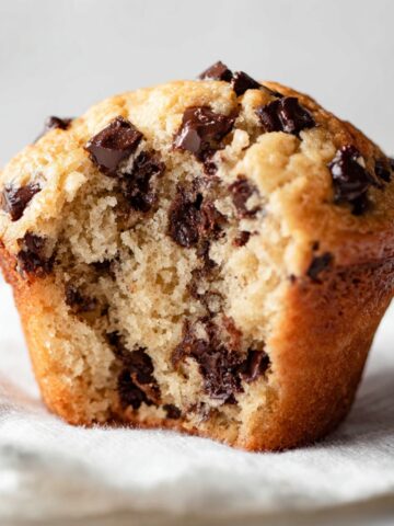 Easy Chocolate Chip Muffins Recipe 2 A close-up shot of a Chocolate Chip Muffins with a bite taken out, showing a soft, fluffy interior filled with chocolate chips.