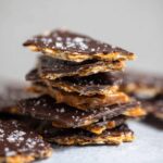 A stack of Chocolate Matzo Crack pieces with a crispy texture, sprinkled with sea salt.