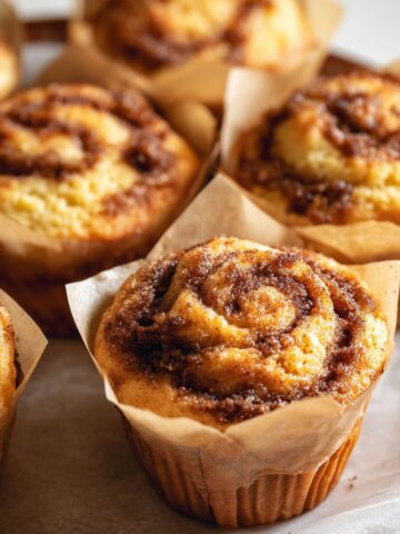 Easy Cinnamon Roll Muffins Recipe 1 A batch of freshly baked Cinnamon Roll Muffins with a golden brown top, lightly sprinkled with sugar.