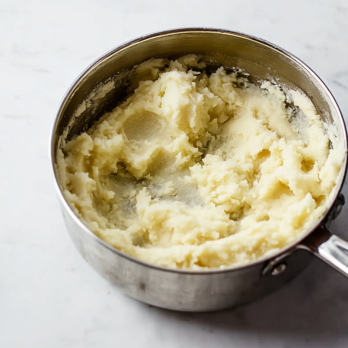 The Best Loaded Meat Pie Recipe 10 Creamy mashed potatoes in a stainless steel pot.